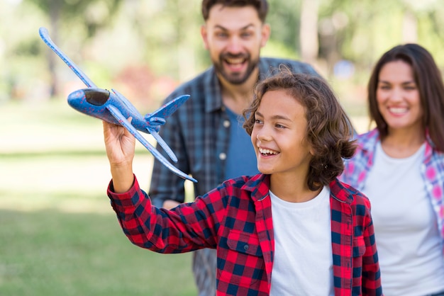 Ragazzo che gioca con l'aereo e i genitori al parco