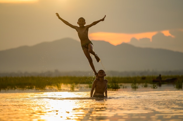 Ragazzo che gioca spruzzi d'acqua nel fiume durante il tramonto, spruzzi d'acqua, Thailandia