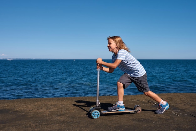 Ragazzo che guida uno scooter su un molo in una giornata di sole