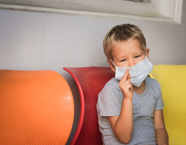 Ragazzo che indossa la maschera monouso facciale per evitare l'infezione virale. Protezione dai virus