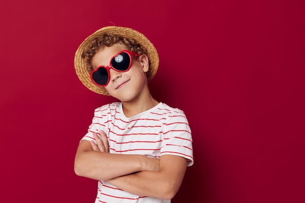 Ragazzo che indossa occhiali da sole che indossa un cappello in posa in stile infantile