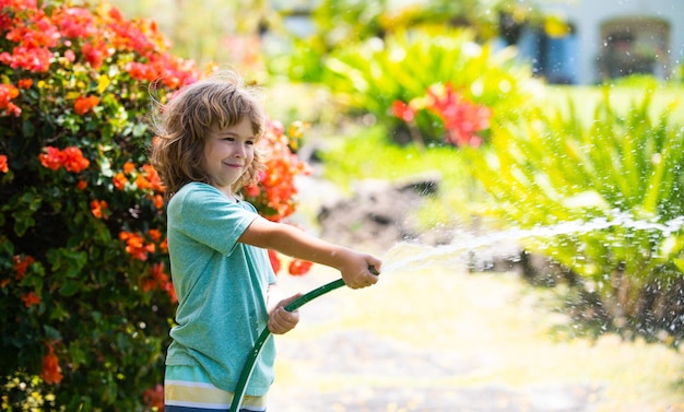 Ragazzo che innaffia le piante in giardino il concetto di gentilezza infantile e infanzia piccolo aiutante adorabile biondo