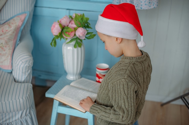 ragazzo che legge un libro con cappello di Babbo Natale