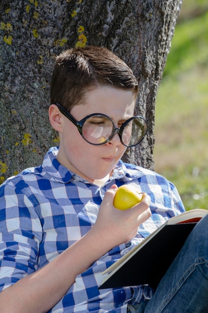 Ragazzo che legge un libro nel bosco con profondità di campo ridotta e spazio di copia