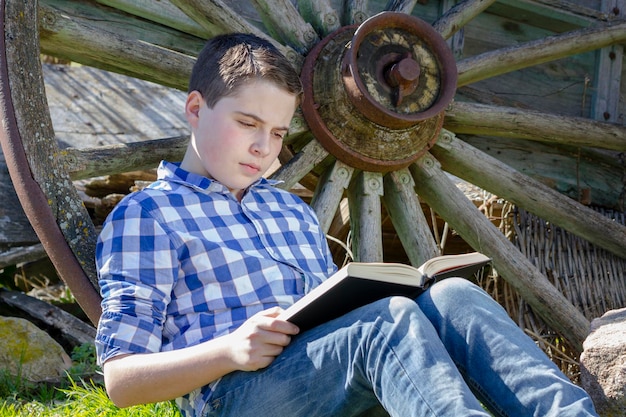 Ragazzo che legge un libro nel bosco con profondità di campo ridotta e spazio di copia