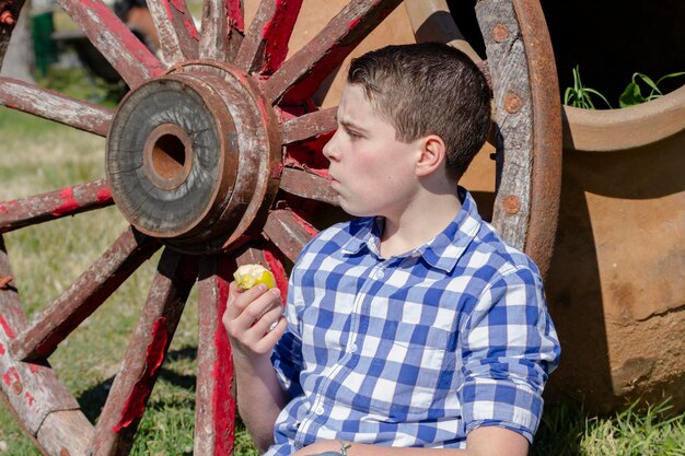 Ragazzo che legge un libro nel bosco con profondità di campo ridotta e spazio di copia