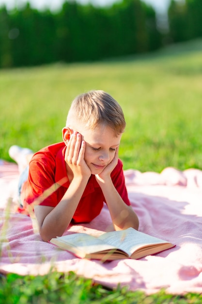 Ragazzo che legge un libro nel parco su uno sfondo di verde