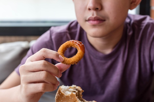 Ragazzo che mangia cipolle fritte