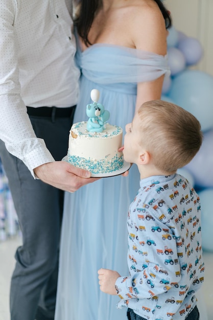 Ragazzo che mangia la sua torta di compleanno Torta bianca e blu. Idea per foto di famiglia