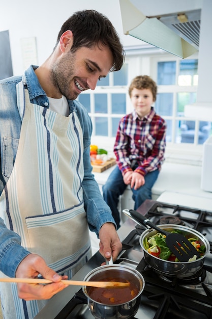 Ragazzo che osserva mentre padre che cucina alimento