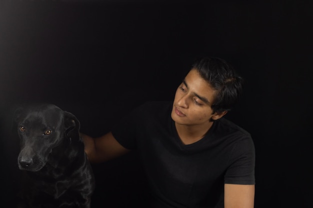 Ragazzo che passa del tempo con il suo cane nero con bellissimi capelli neri lucenti