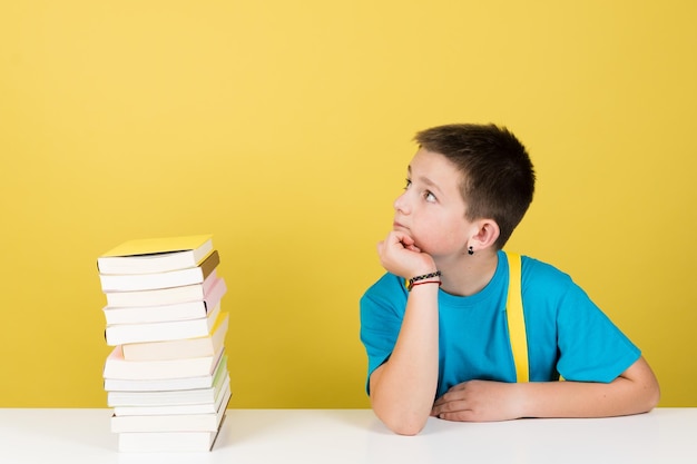 Ragazzo che pensa accanto a una pila di libri