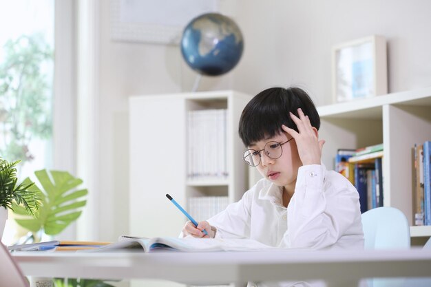 Ragazzo che pensa attentamente concentrandosi e studiando duramente alla sua scrivania