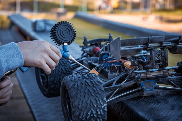 Ragazzo che pulisce la sua automobile RC con un compressore d'aria