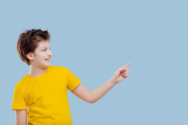 Ragazzo che punta il dito sul lato sinistro, con una maglietta gialla isolata sul blu