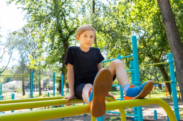 Ragazzo che riposa seduto sulle barre ginniche nel parco