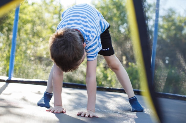 Ragazzo che salta sul trampolino il bambino gioca su un trampolino all'aperto