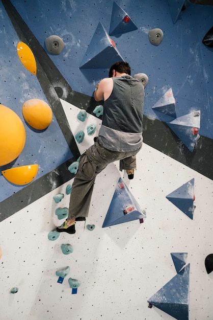 Ragazzo che scala una parete in una parete di arrampicata indoor