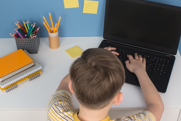 Ragazzo che scrive sul computer portatile mentre fa i compiti