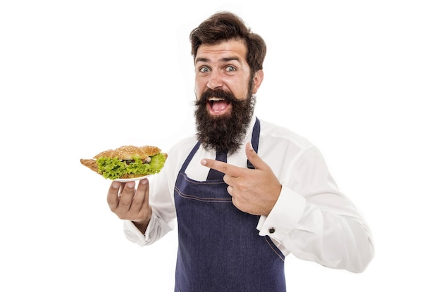 Ragazzo che serve croissant ripieni di lattuga e verdure fresche Cibo sano Croissant francese tradizionale Uomo cameriere barbuto indossare grembiule porta piatto con piatto Delizioso croissant Cafe concept