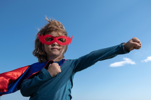 Ragazzo che si diverte all'aperto con un mantello da super uomo che gioca al successo del supereroe e al concetto di vincitore