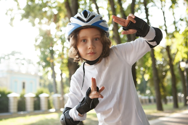 Ragazzo che si diverte all'aperto nel parco indossando pattini protettivi e casco