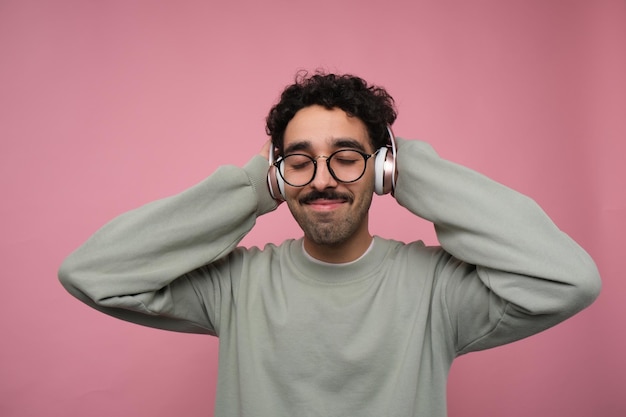 Ragazzo che si gode la musica in cuffia sullo sfondo rosa