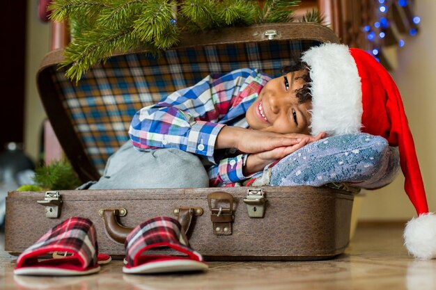 Ragazzo che si sveglia in valigia. Il sorriso mattutino del piccolo Babbo Natale. La mattina più felice dell'anno. Ansioso di vedere i regali.