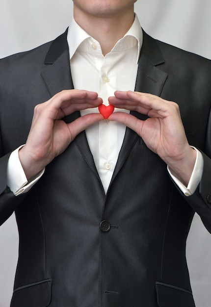 Ragazzo che tiene un cuore rosso decorativo. Idea di San Valentino