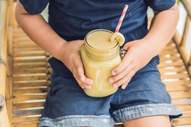 Ragazzo che tiene un frullato di banana, concetto di corretta alimentazione.