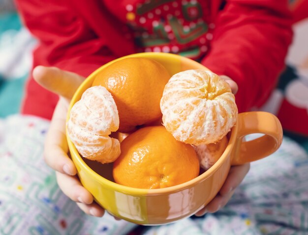 Ragazzo che tiene una tazza con mandarini