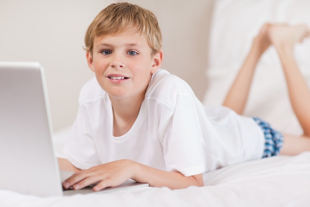 Ragazzo che utilizza un computer portatile in una camera da letto