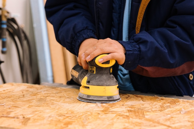 Ragazzo che utilizza una levigatrice elettrica