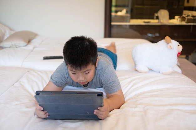Ragazzo cinese asiatico che gioca a smartphone, bambino usa il telefono e gioca, gioco dipendente e cartone animato