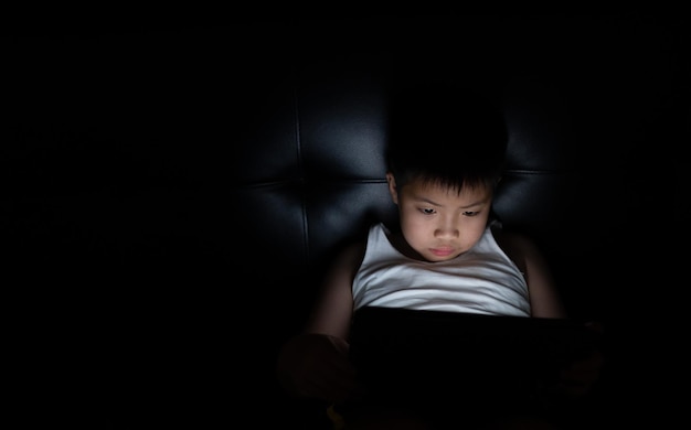 ragazzo cinese asiatico che gioca con lo smartphone bambino usa il telefono e gioca gioco dipendente e cartone animato