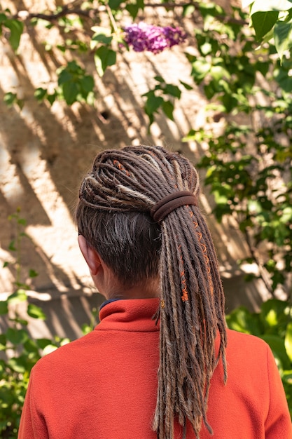 Ragazzo con acconciatura di dreadlocks intrecciati moda creativa che indossa maglione arancione