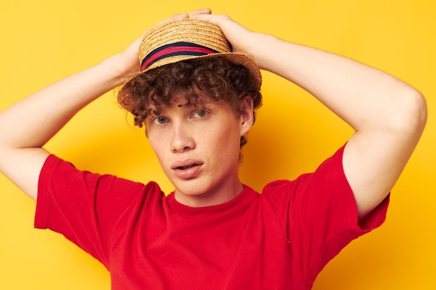 Ragazzo con capelli ricci rossi abbigliamento casual cappello in posa sfondo giallo inalterato
