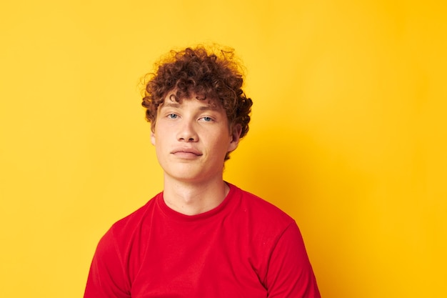 Ragazzo con capelli ricci rossi emozioni maglietta rossa cappello studio sfondo giallo inalterato