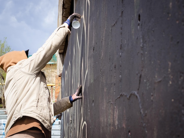 Ragazzo con cappuccio e occhiali neri scrive graffiti