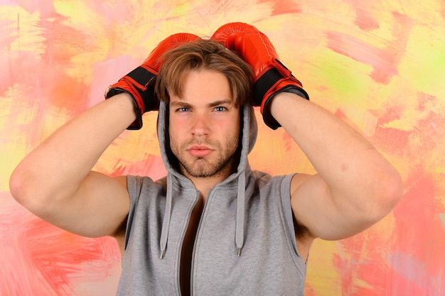 Ragazzo con cappuccio grigio senza maniche indossa guanti da boxe in pelle rossa