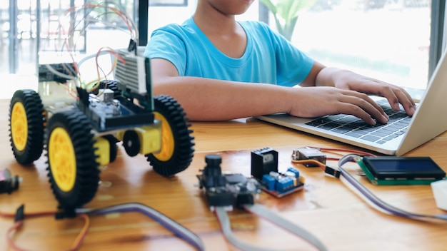 Ragazzo con computer tablet pc programmazione giocattoli elettrici e robot da costruzione.