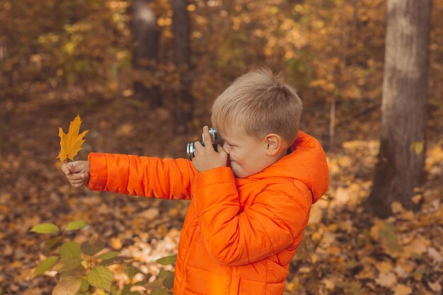 Ragazzo con fotocamera retrò per scattare foto all'aperto nella natura autunnale. Concetto di tempo libero e fotografi