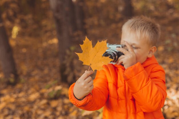 Ragazzo con fotocamera retrò per scattare foto all'aperto nella natura autunnale. Concetto di tempo libero e fotografi