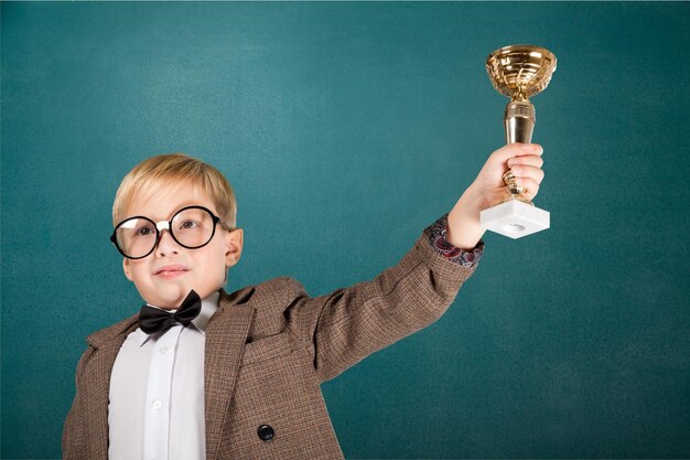 Ragazzo con gli occhiali che tiene il trofeo sullo sfondo della lavagna