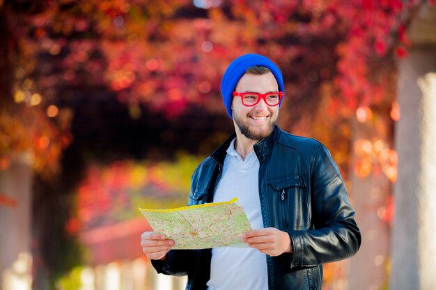 ragazzo con gli occhiali e cappello con mappa in un parco