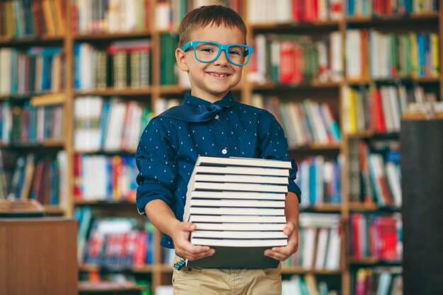 Ragazzo con gli occhiali e la pila di libri