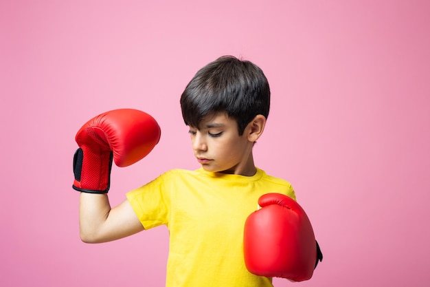 Ragazzo con guantoni da boxe in mostra muscolare