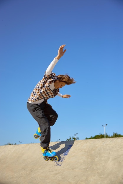 Ragazzo con i pattini che fa acrobazie su una rampa di cemento in uno skate park.