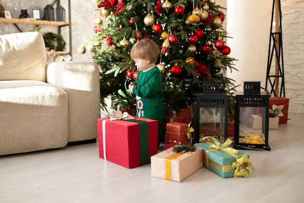 Ragazzo con i regali di Natale accanto all'albero