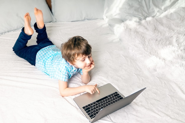 Ragazzo con il computer portatile a letto